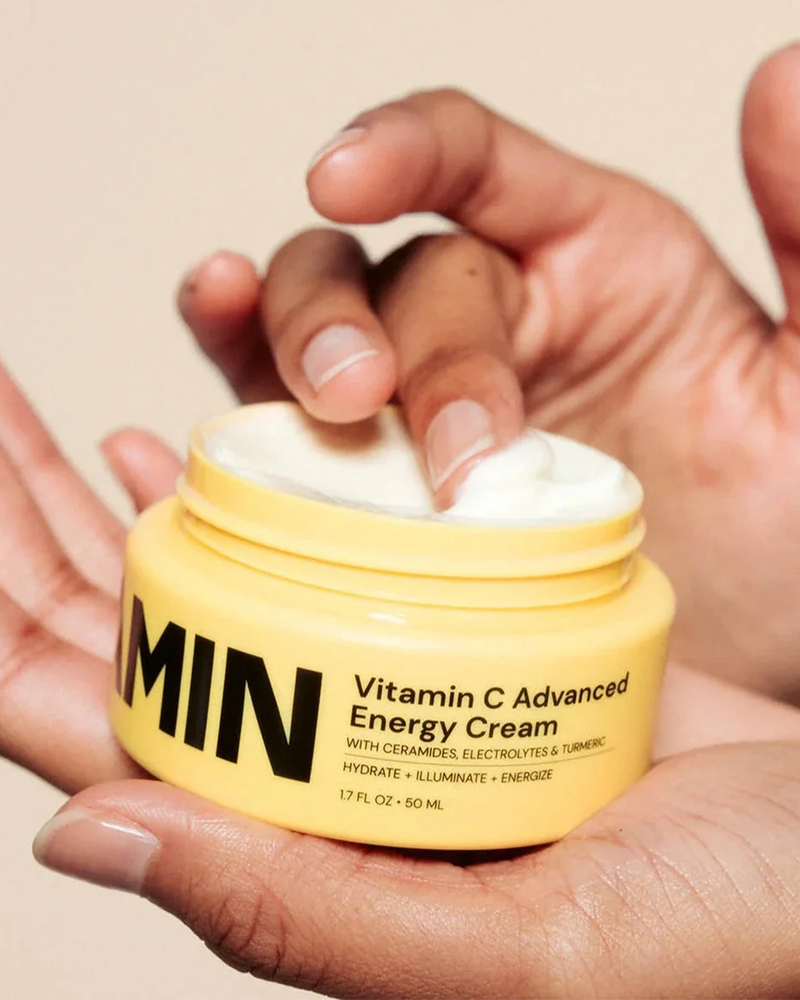 Hand scooping Advanced Brightening Moisturizer from jar, highlighting creamy texture. Perfect for deep hydration and skin brightening routines.
